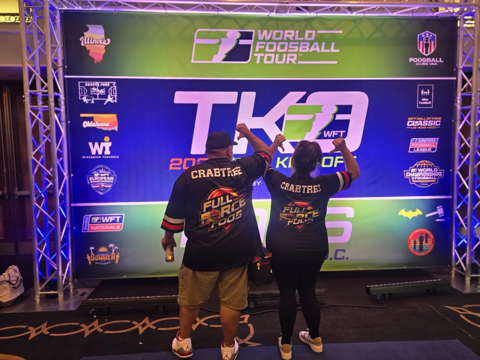 Two Full Force Foos members proudly showing their club jerseys at a World Foosball Tour event